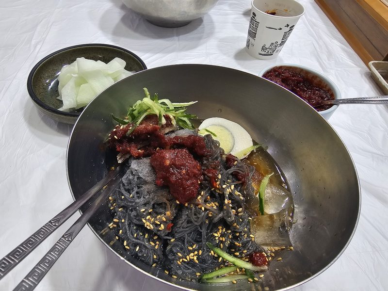 냉면 위에 듬뿍 얹은 빨간 명태회 고명과 무절임